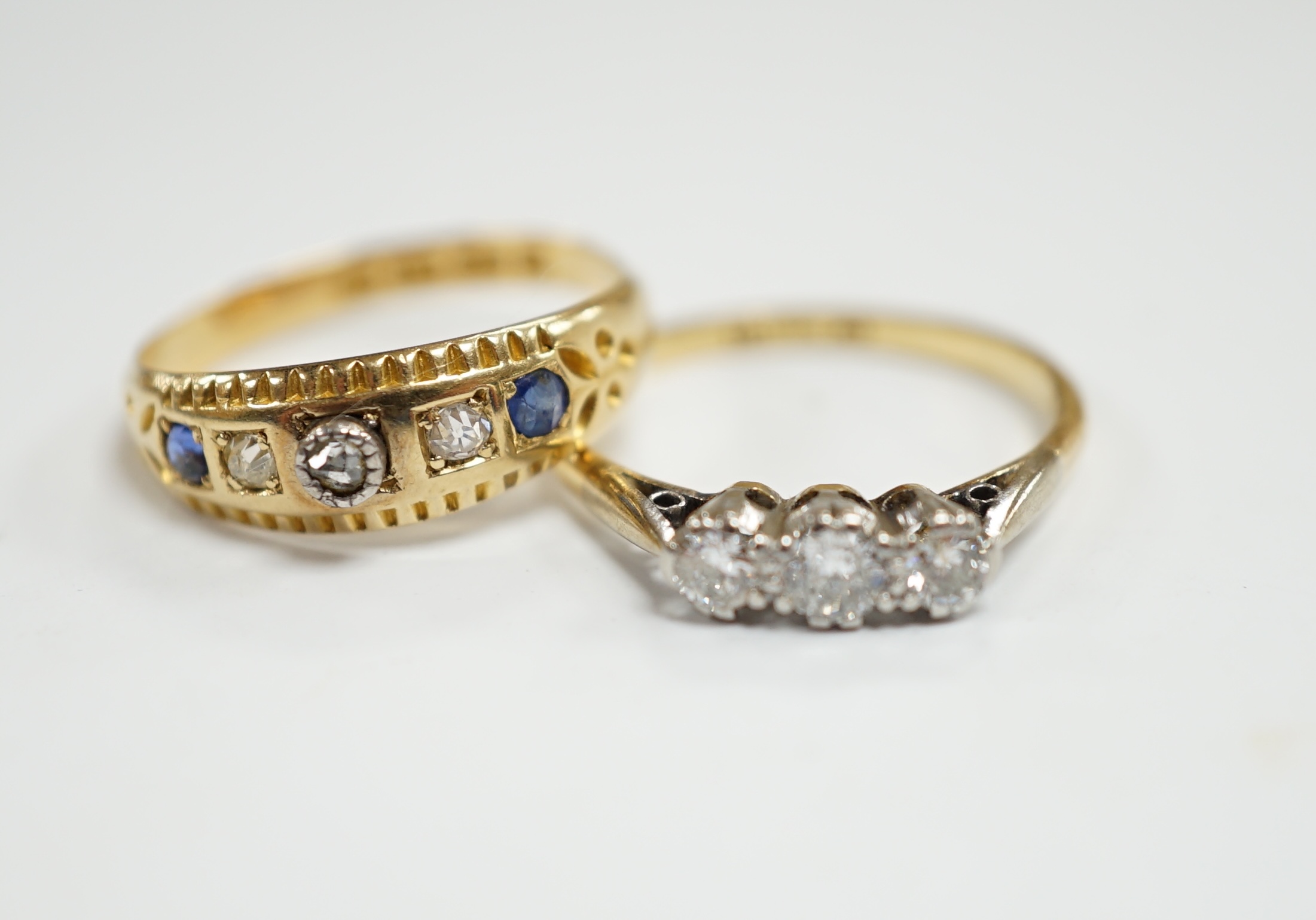 An 18ct, plat and three stone diamond set ring, size K and a late Victorian 18ct gold three stone diamond and two stone sapphire set ring, size K, gross weight 4.1 grams.